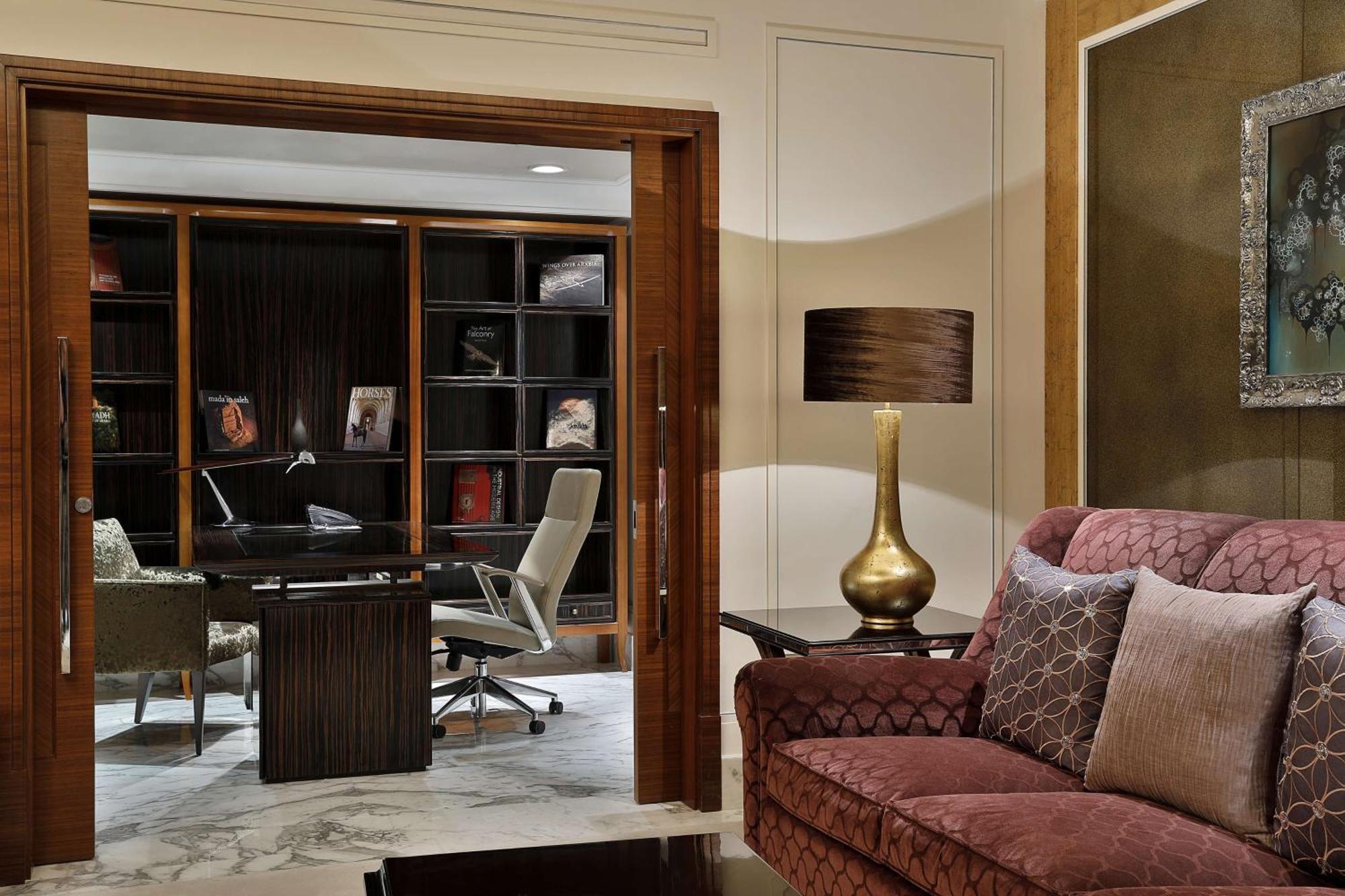 Hilton Riyadh Hotel & Residences Kültér fotó The photo shows a stylish and modern interior space that appears to be a home office or study. In the foreground, there is a comfortable burgundy sofa with decorative pillows. Behind the sofa, there is a doorway leading to the office area, which incl