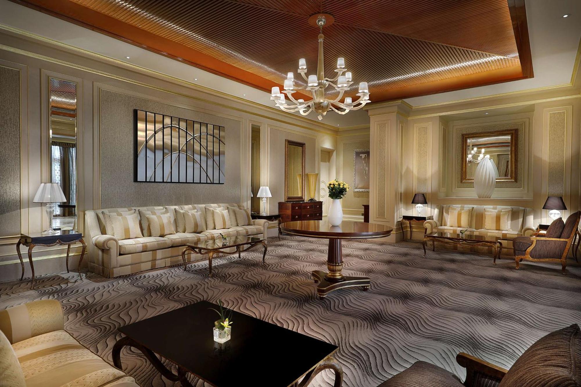 Hilton Riyadh Hotel & Residences Kültér fotó The photo depicts an elegant and well-appointed living room or lounge area. It features a soft color palette with beige and cream tones throughout. 

1. **Furniture**: There are two plush sofas, a round wooden coffee table in the center, and a couple