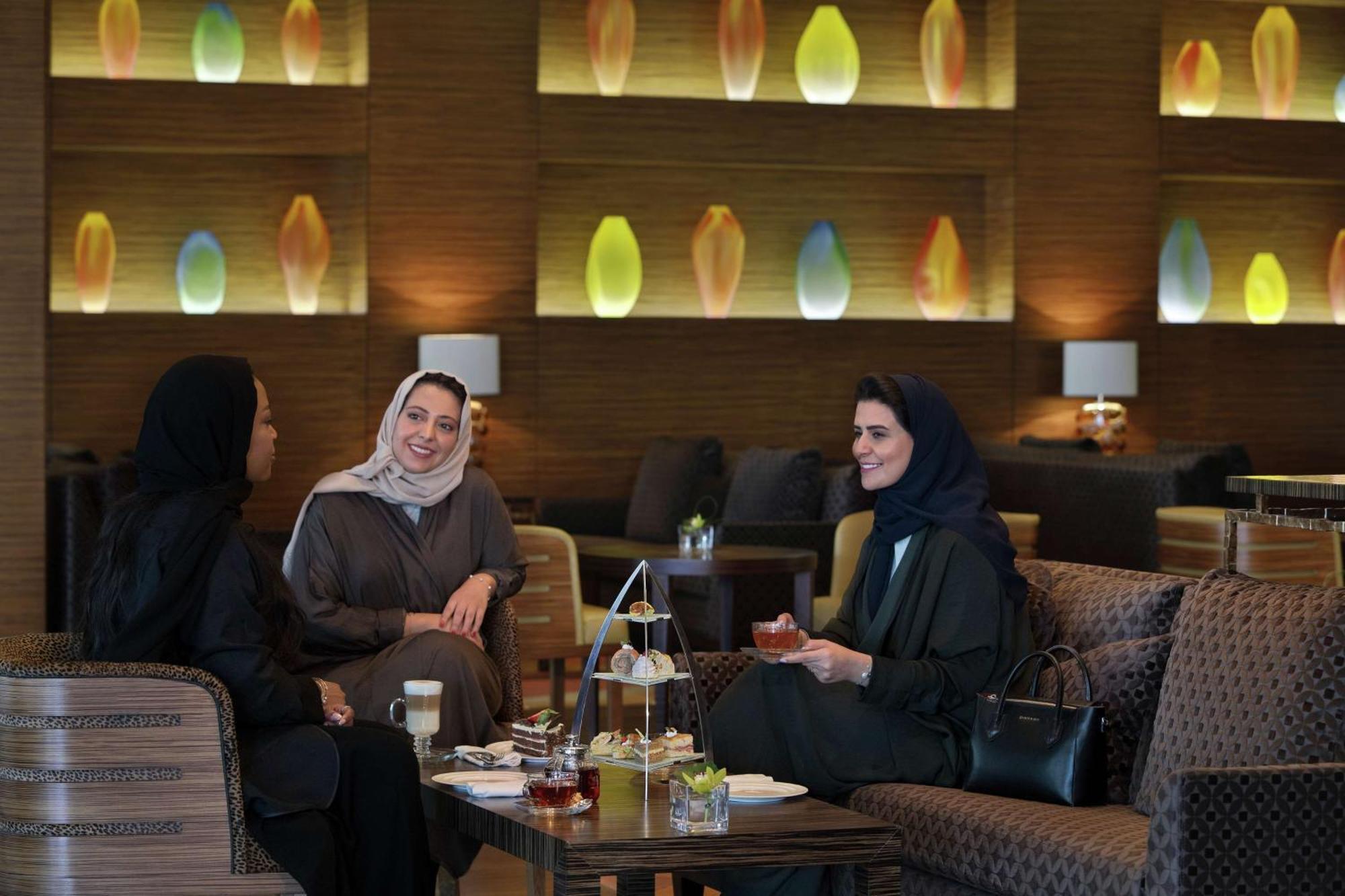 Hilton Riyadh Hotel & Residences Kültér fotó The photo shows three women sitting together in a cozy, well-decorated lounge. They appear to be enjoying each other's company, engaged in conversation and possibly sharing tea or refreshments. The setting features soft, modern lighting with decorati