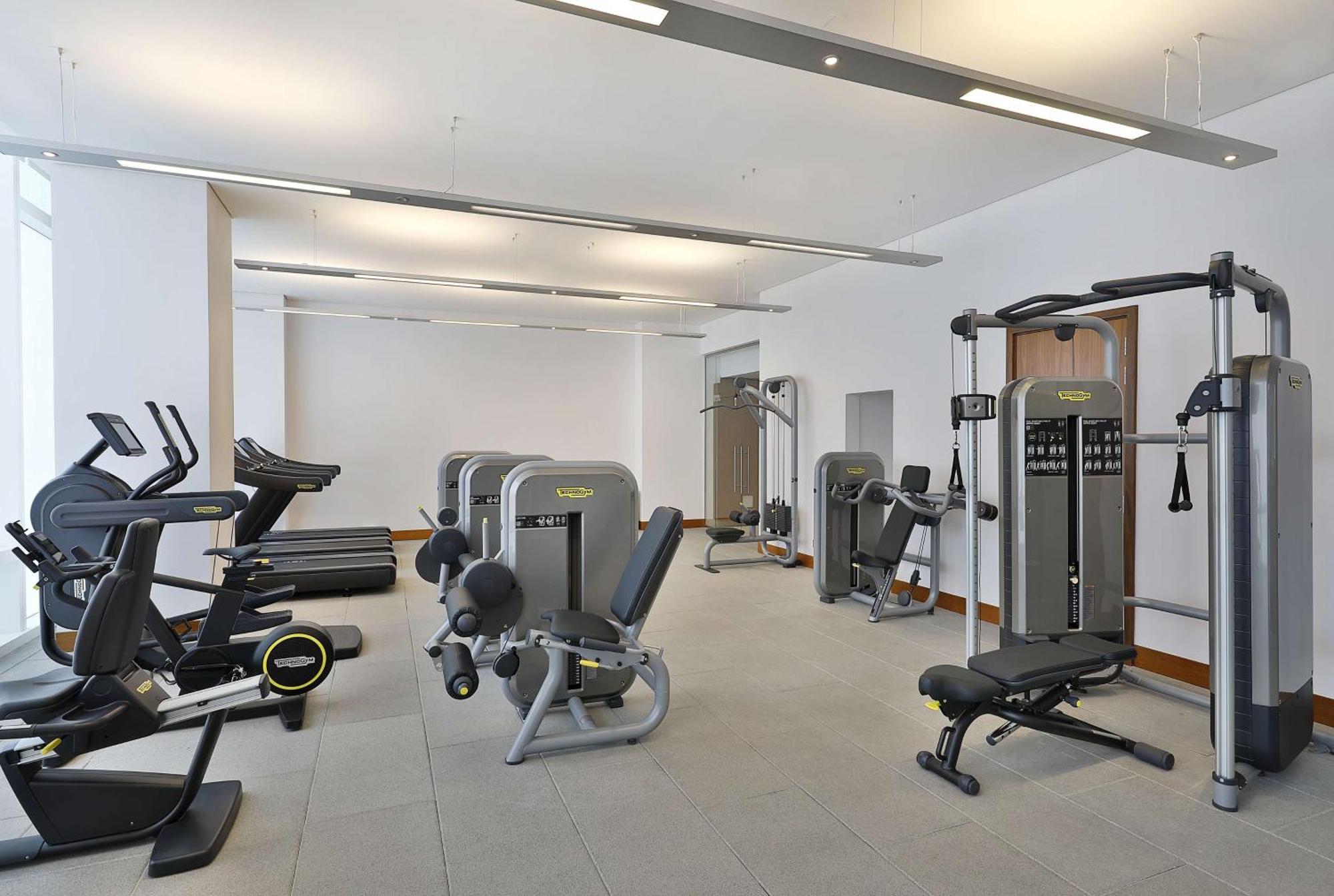 Hilton Riyadh Hotel & Residences Kültér fotó The photo shows a modern gym or fitness center with various exercise equipment. On the left, there are several treadmills, while the center features a range of weight machines. There is a multi-station gym equipment, and a bench press is also visible
